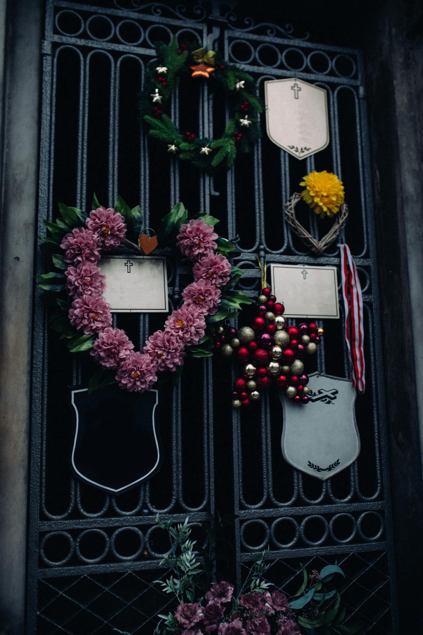 A gate adorned with floral and festive wreaths symbolizing remembrance and memorial.
