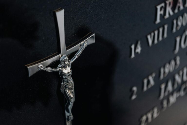Detailed photo of a cross on a tombstone featuring engraved text, representing religious themes.